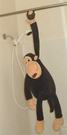 Monkey hangs from shower curtain rod via magnet.